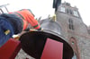 Mitarbeiter einer Baufirma stellen mit einem Kran eine historische Stahlglocke als Blickfang vor die Neubrandenburger Konzertkirche. Die fast 100 Jahre alte Glocke ist knapp vier Tonnen schwer.