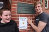Grundschüler Hubertus Weising (links) und Markus Höft, im Freiwilligen Ökologischen Jahr, zeigen stolz das neue Eingangsschild.
