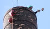 In Seilen hängend und gestützt auf die Steigleiter tragen die Industriekletterer abwechselnd Stein für Stein des Turms ab.