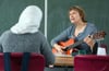 Die Russlanddeutsche Valentina Ravva (mit Gitarre) kommt ehrenamtlich in die Schule.
