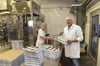 Praktikantin Ombeline Lengronne aus Frankreich und Gunnar Hemme stehen an der Anlage, wo Joghurt verpackt wird.