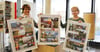 Stadtinfo-Chefin Antje Lang (links) und Mitarbeiterin Simone Dethloff präsentieren die Jahresplakate.