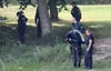 Polizisten, darunter ein Taucher, suchen im Uferbereich des Sees in Pragsdorf bei Neubrandenburg nach Tatgegenständen.