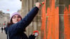 Eine Klimaaktivistin bemalt das Brandenburger Tor mit oranger Farbe.