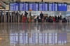 Passagiere stehen am Münchener Flughafen beim Check-in.