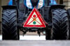 Ein durchgestrichenes Verkehrsschild mit einer Ampel hängt während einer Demonstration von Landwirten an einem Traktor.