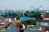 Hinter den Häusern von Rostock-Warnemünde ragen die Schiffskräne des Überseehafens in die Lüfte.